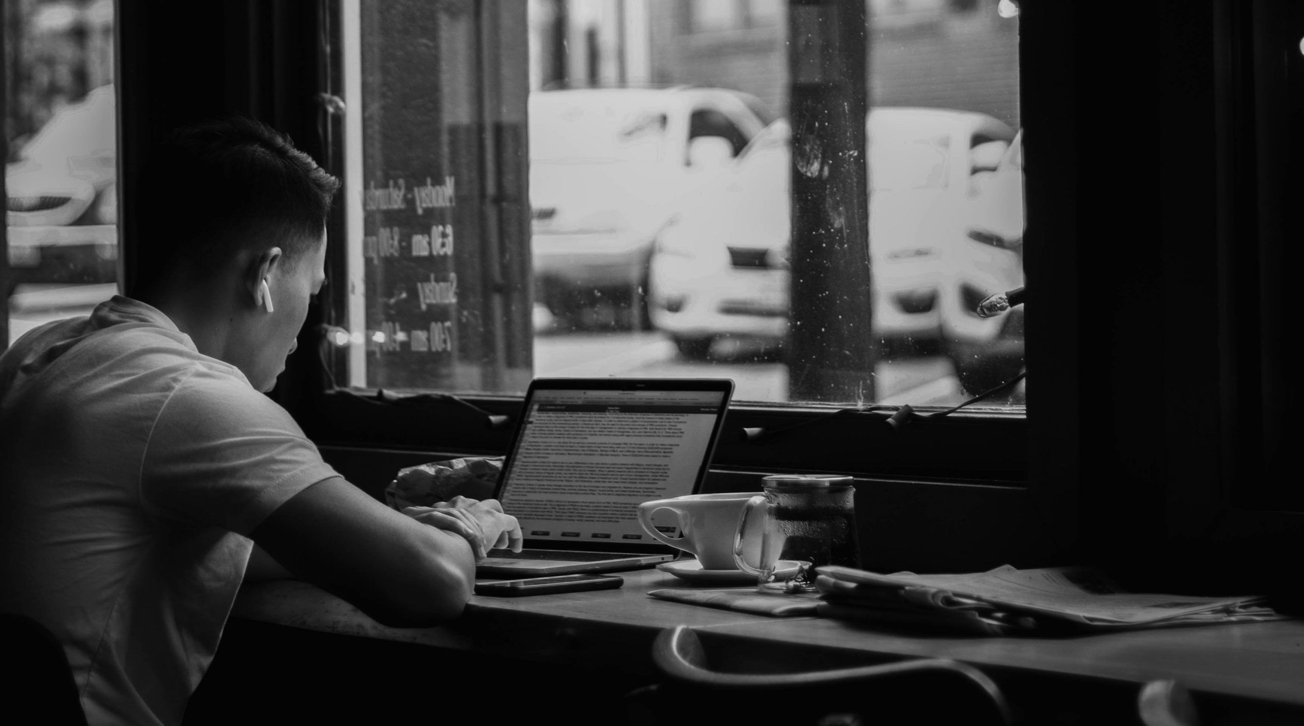 black and white image of person using laptop