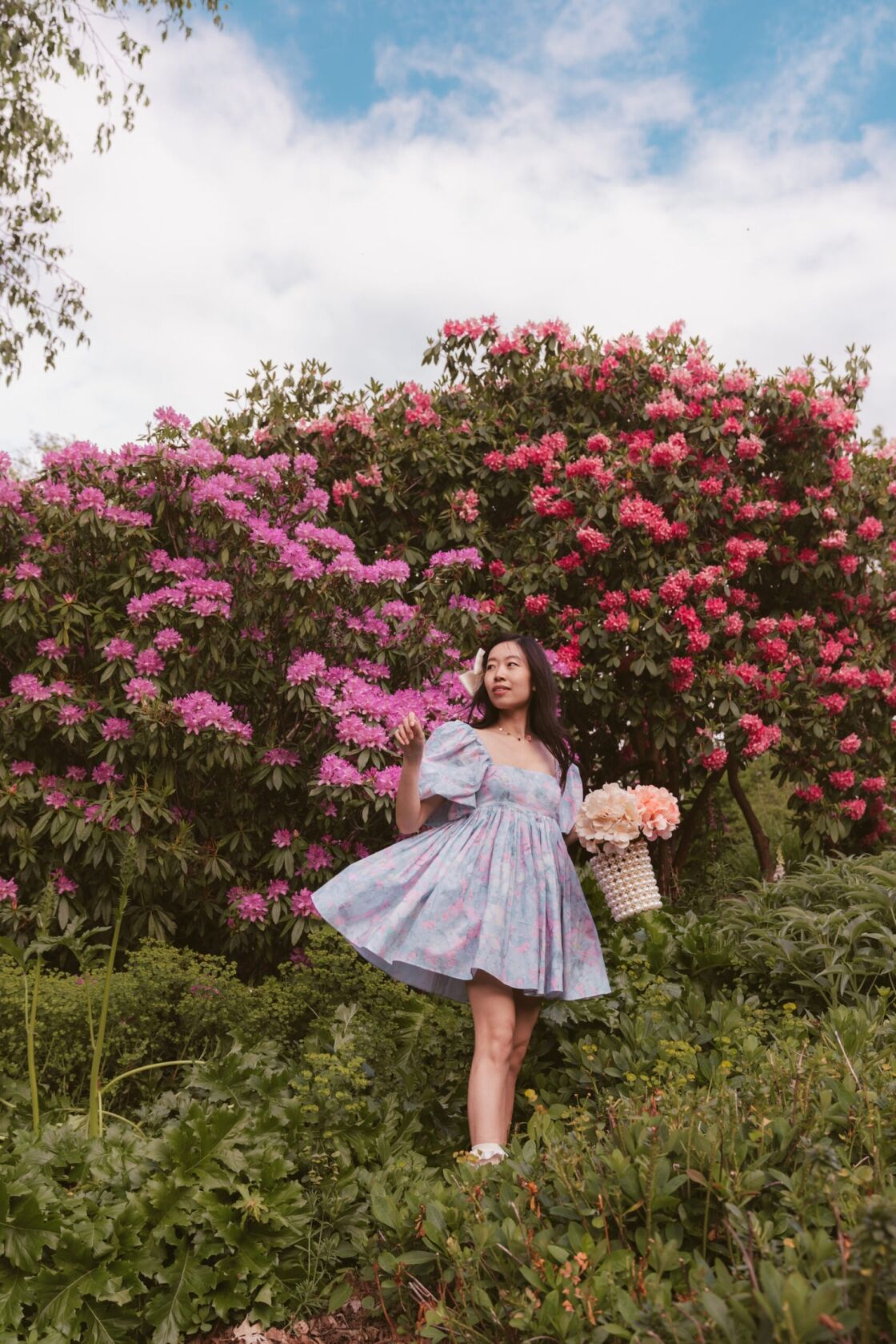 Girl with pastel dress in front of rhododendron flowers